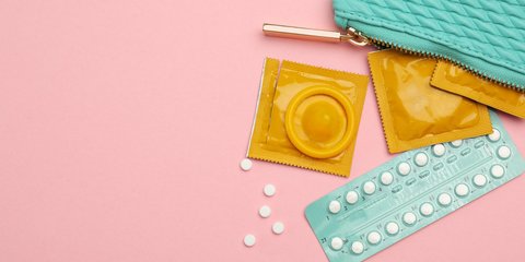 Kondome und Antibabypillen in einem türkisen Toiletttascherl auf rosa Hintergrund