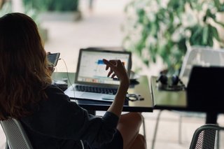 Frau am Laptop, telefoniert am Handy