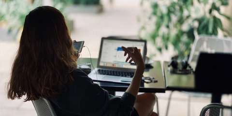 Frau am Laptop, telefoniert am Handy